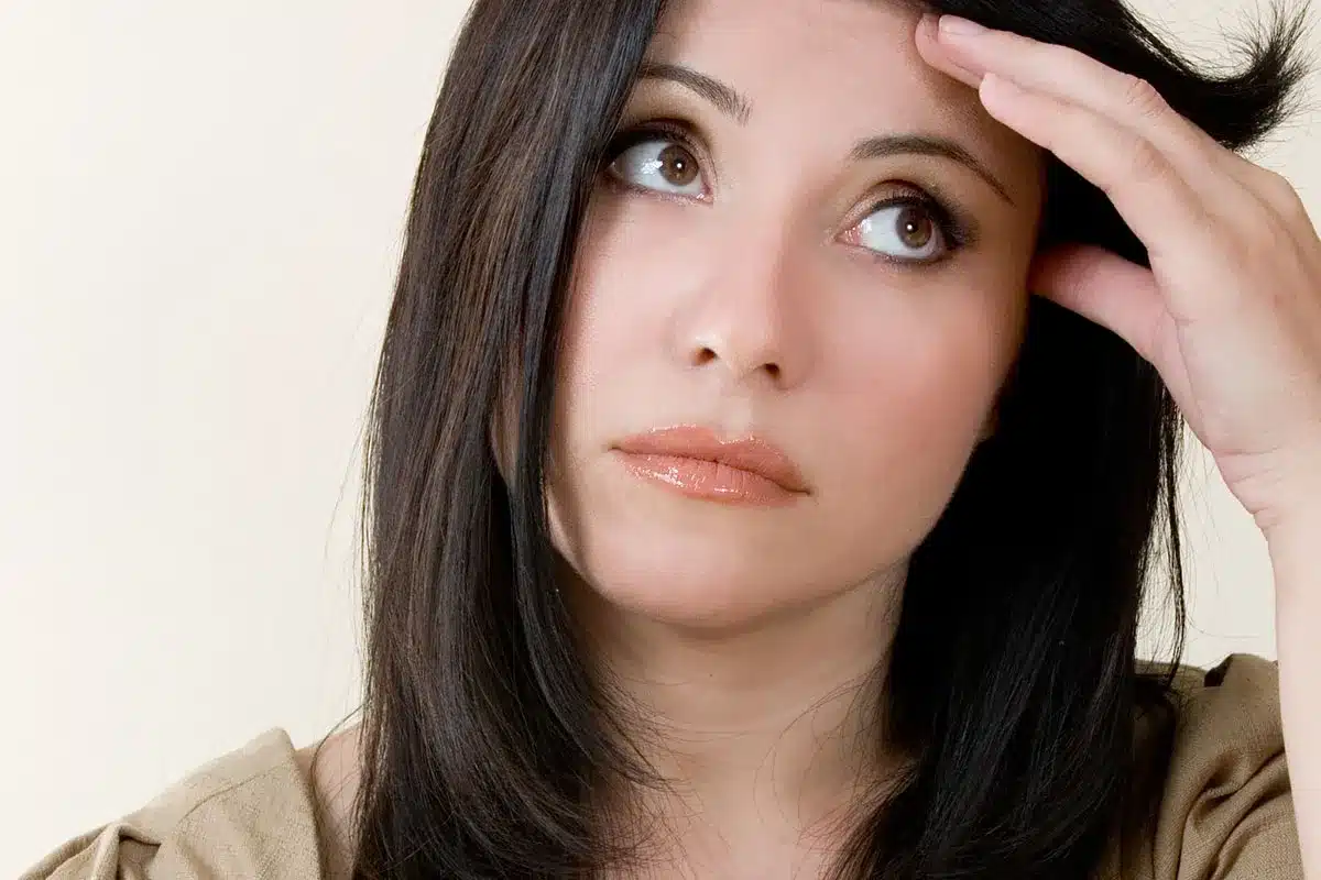 Pensive woman touching her forehead.