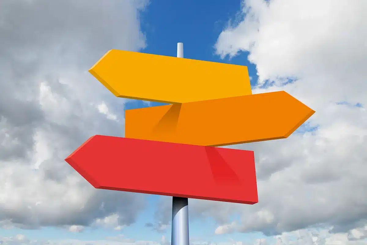 Three directional signs against sky.