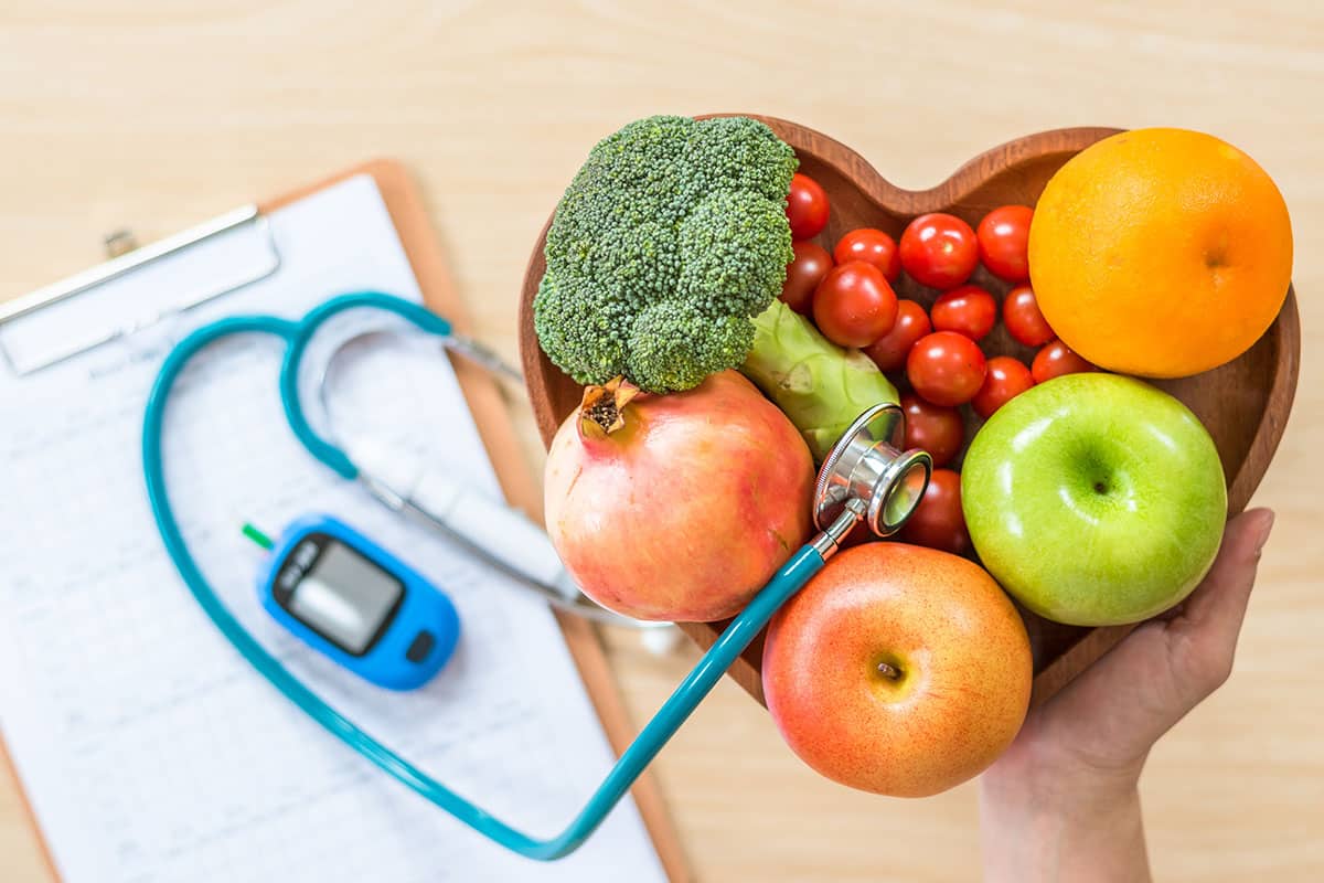 Heart-shaped bowl of healthy fruits and vegetables.