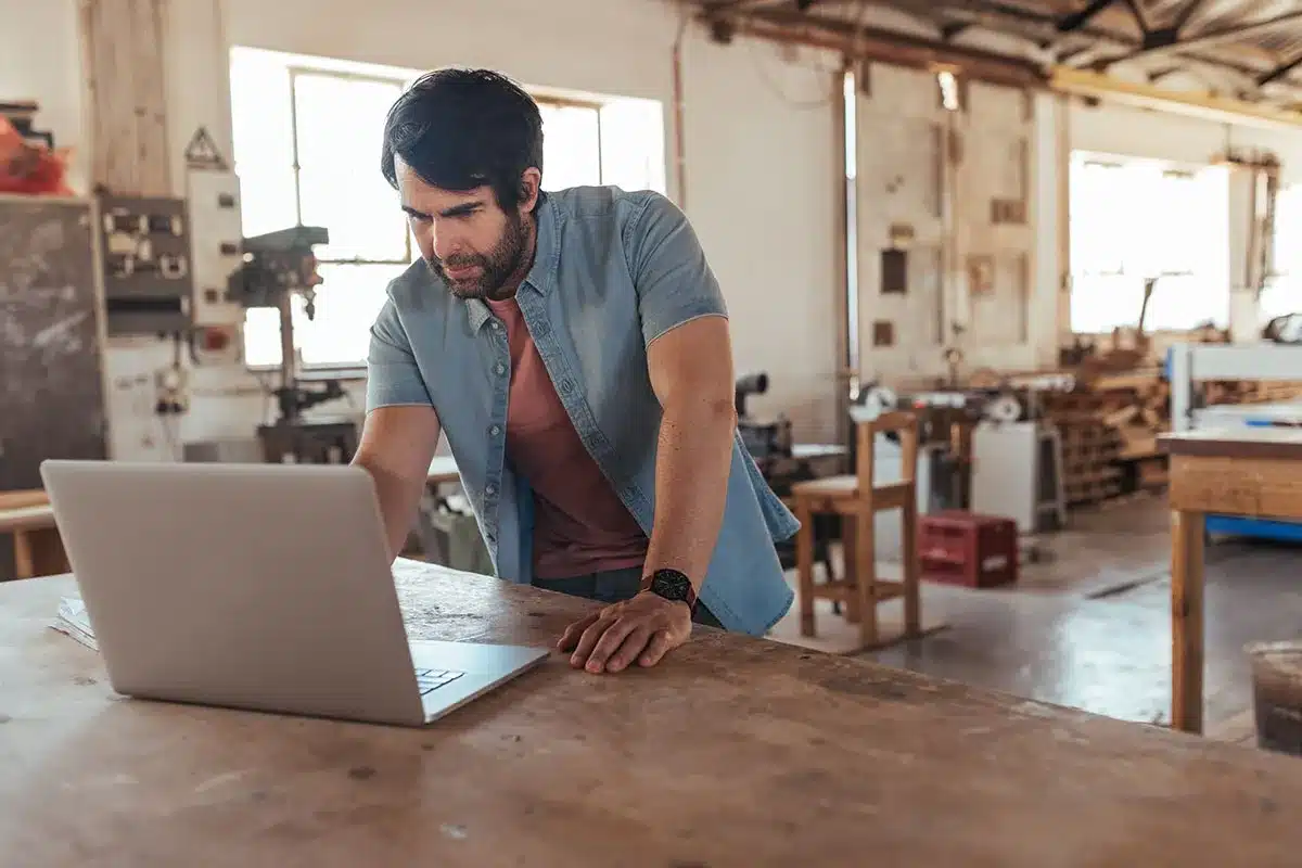 Man working on laptop in woodshop.