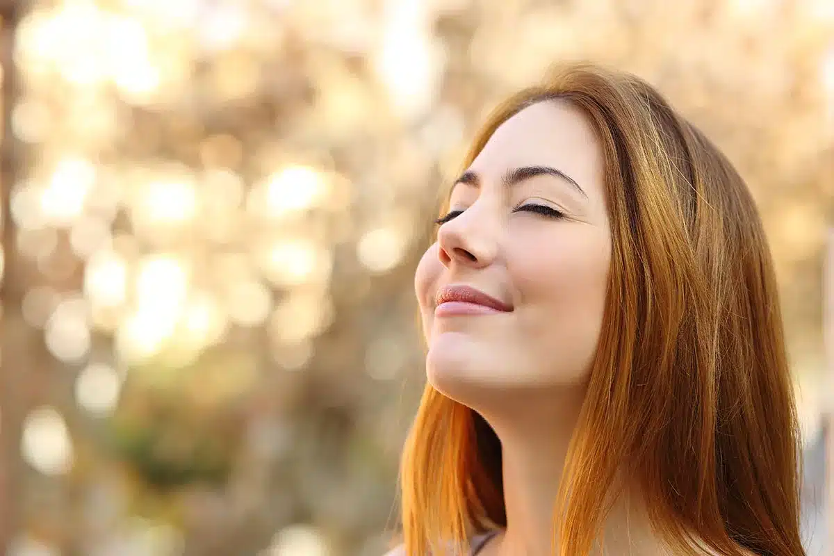 Young woman breathing fresh air outdoors.