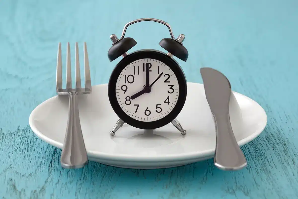 Alarm clock on a plate with fork and knife.