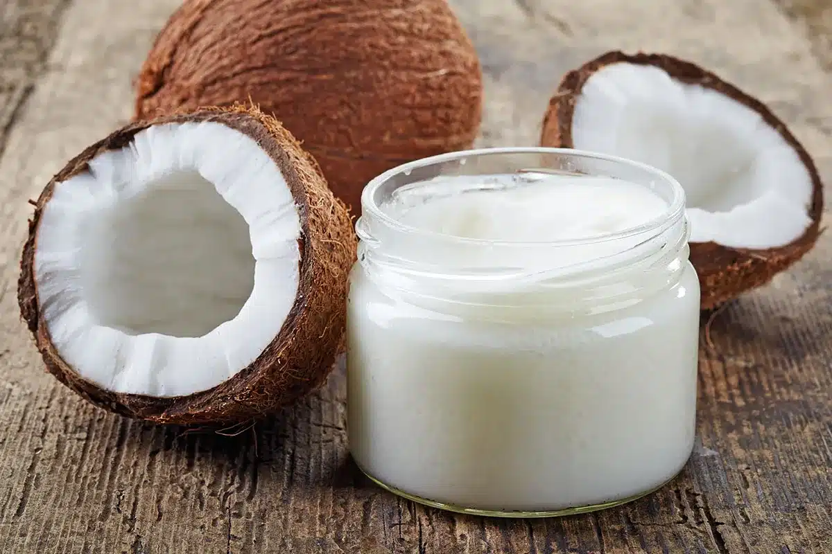 Jar of coconut oil with coconuts.