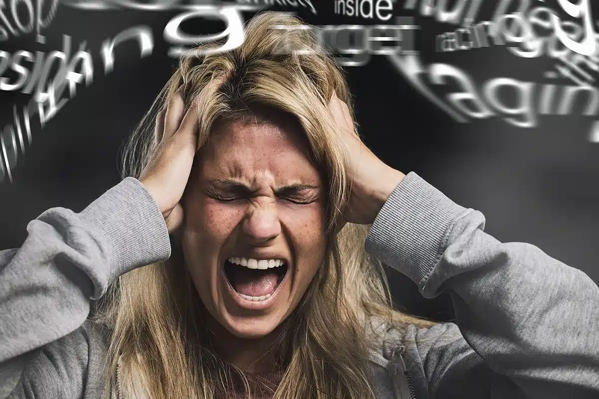 Stressed woman with hands on head.