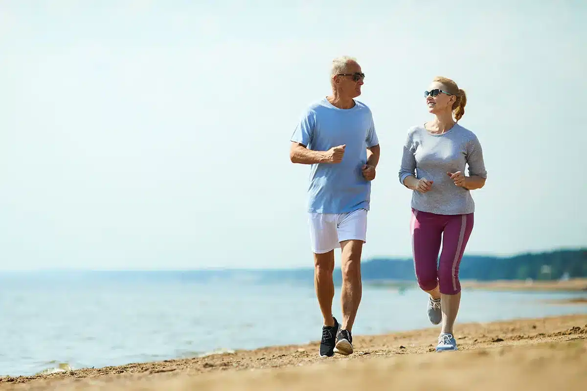 Senior couple jogging on the beach.