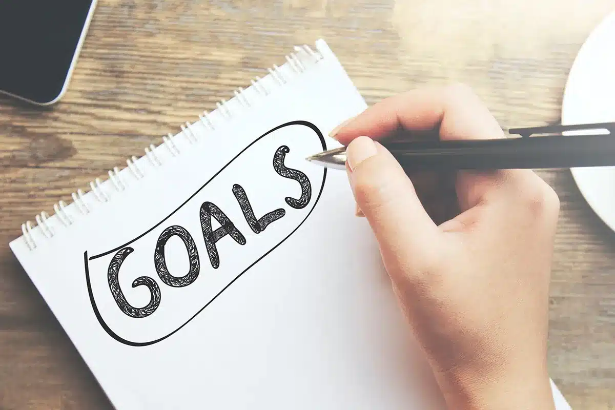 Hand writing "Goals" in a notebook.