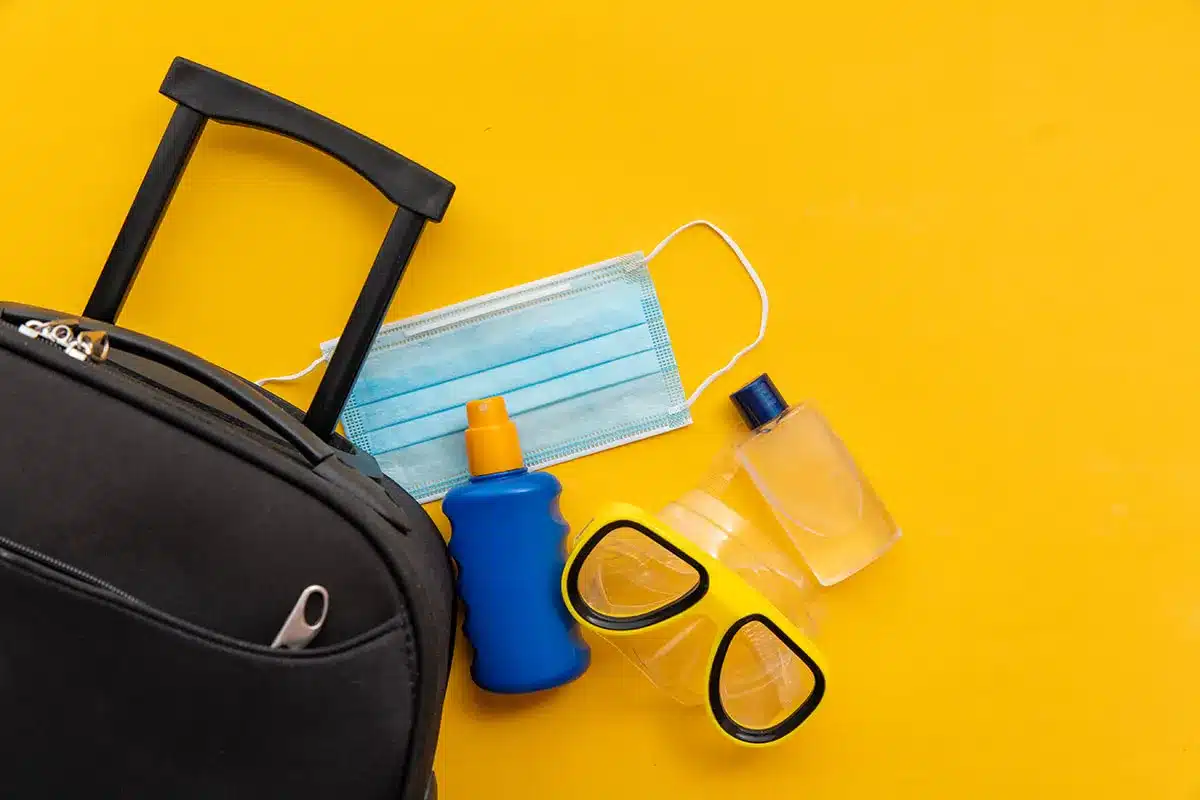 Travel essentials: suitcase, mask, sunscreen.