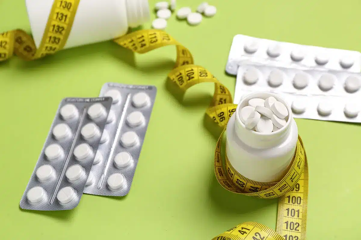 Pills, measuring tape, weight loss concept.