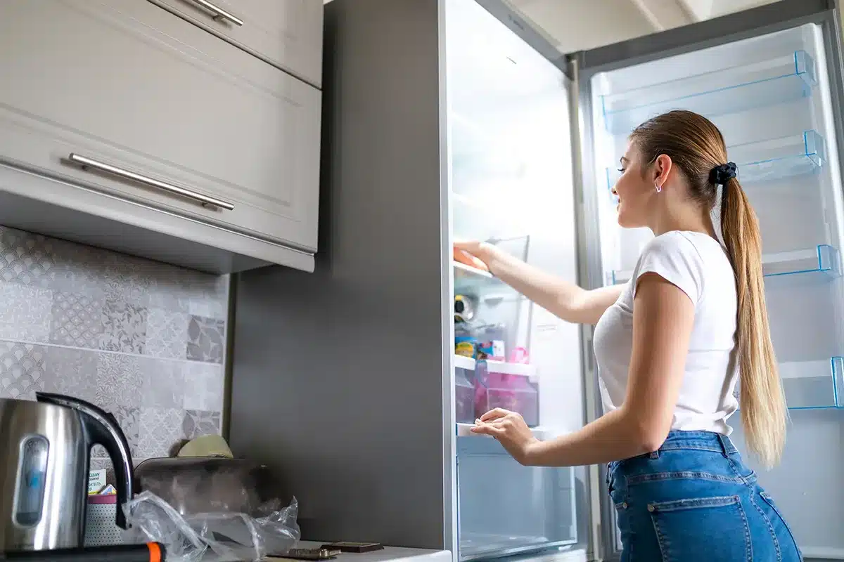 Woman looking for food in refrigerator.