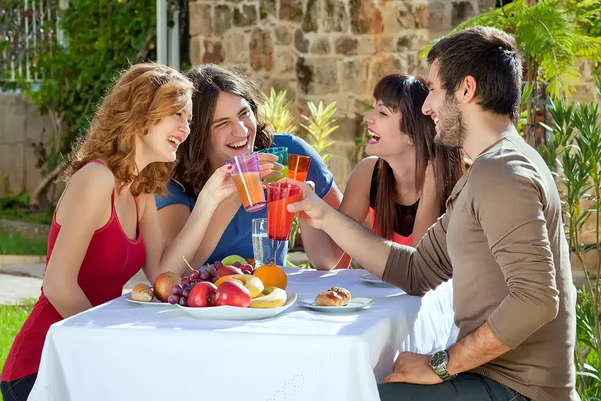 Friends enjoying a meal and drinks outdoors.