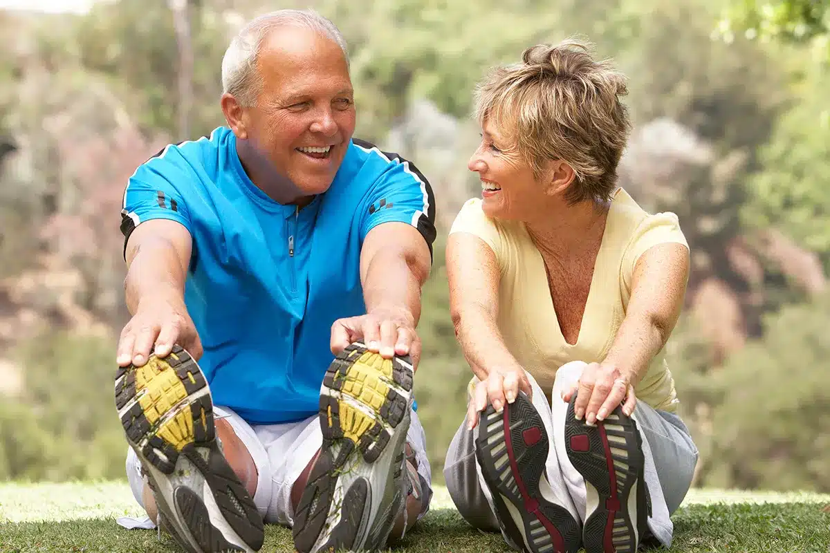 Senior couple stretching in park.