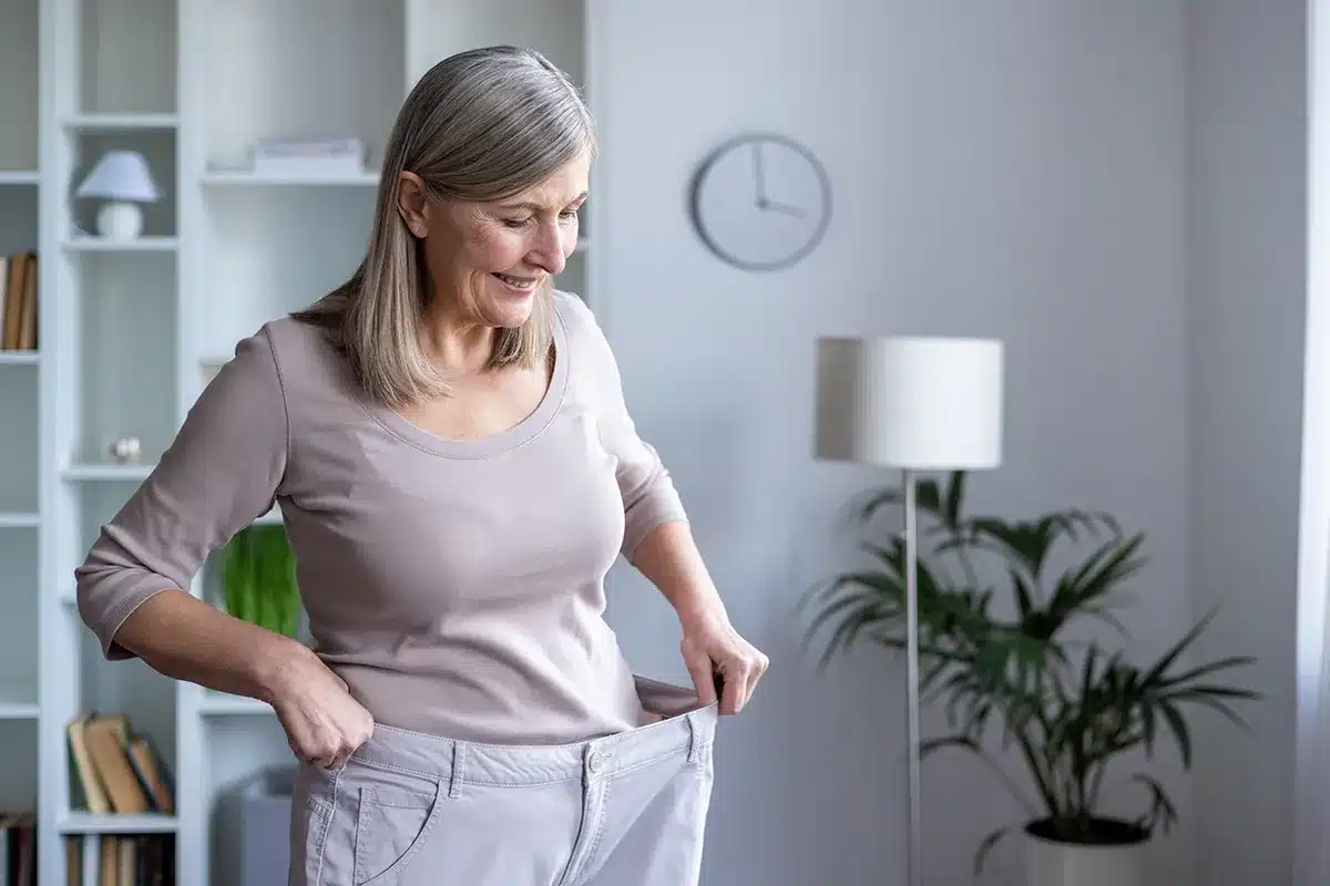 Woman showing weight loss in loose pants.