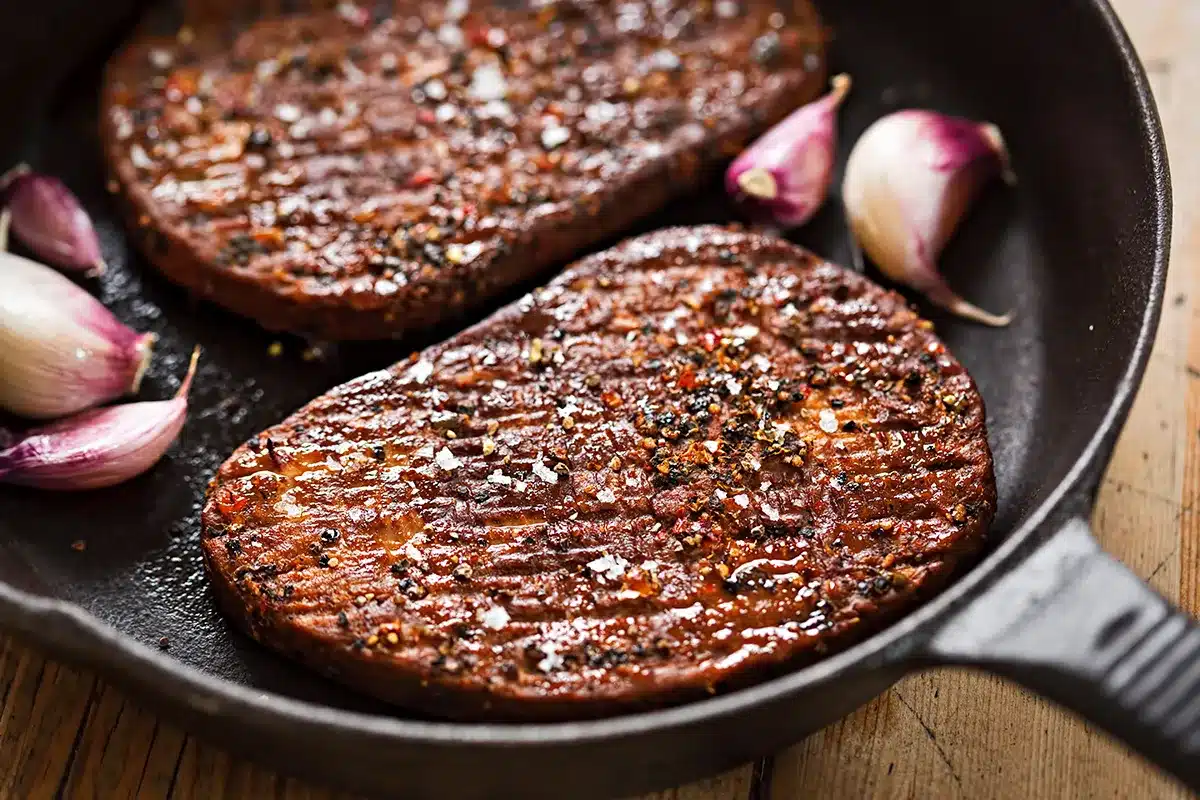 Vegan steaks cooking in a pan.