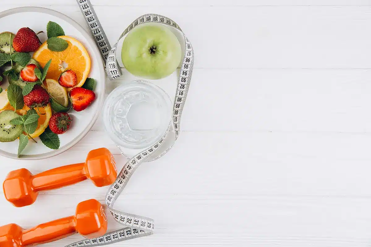 Healthy fruit salad, water, dumbbells, tape measure.
