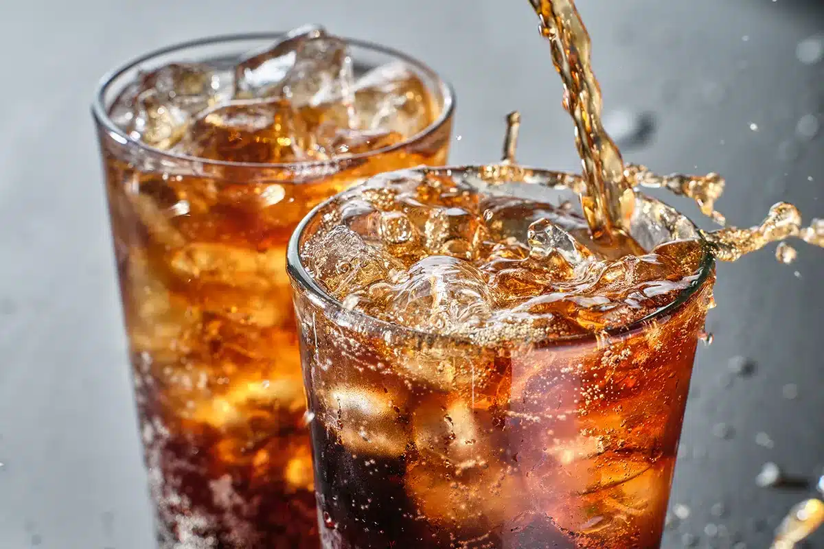 Close-up of cola being poured into a glass filled with ice.