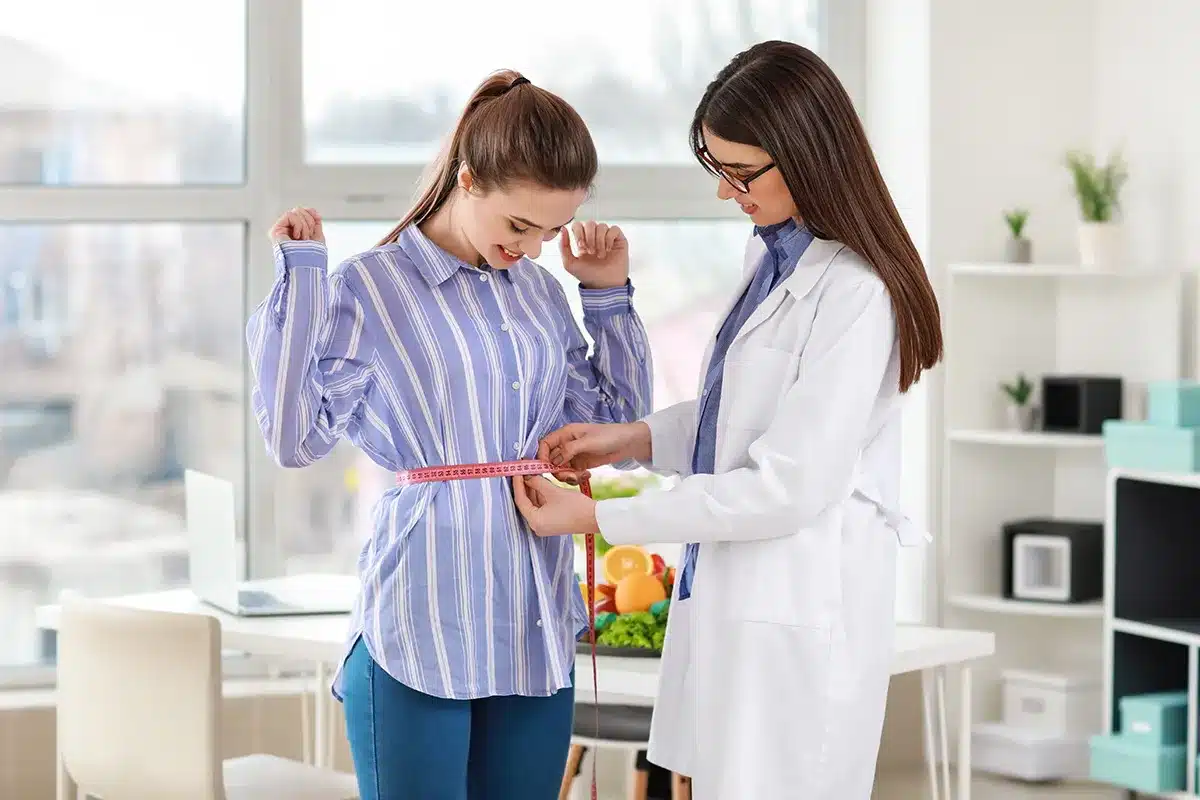 Nutritionist measuring client's waist.