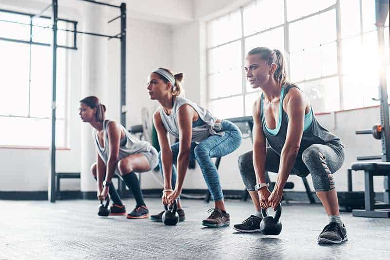 three women working out with weights at the gym