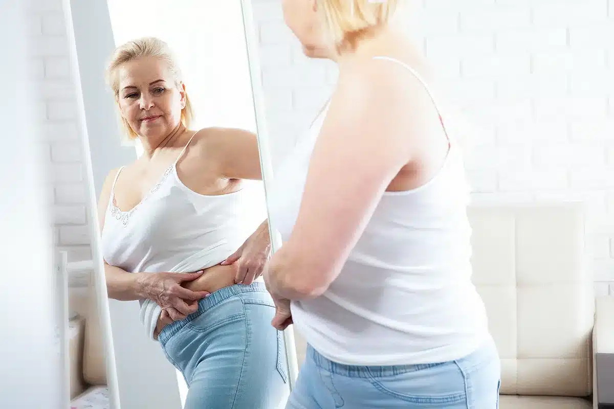 Woman checking her body fat in mirror.