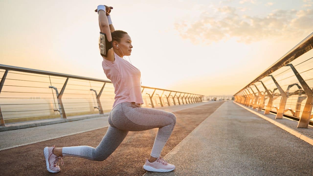 Female athlete in sportswear stretching her arms up