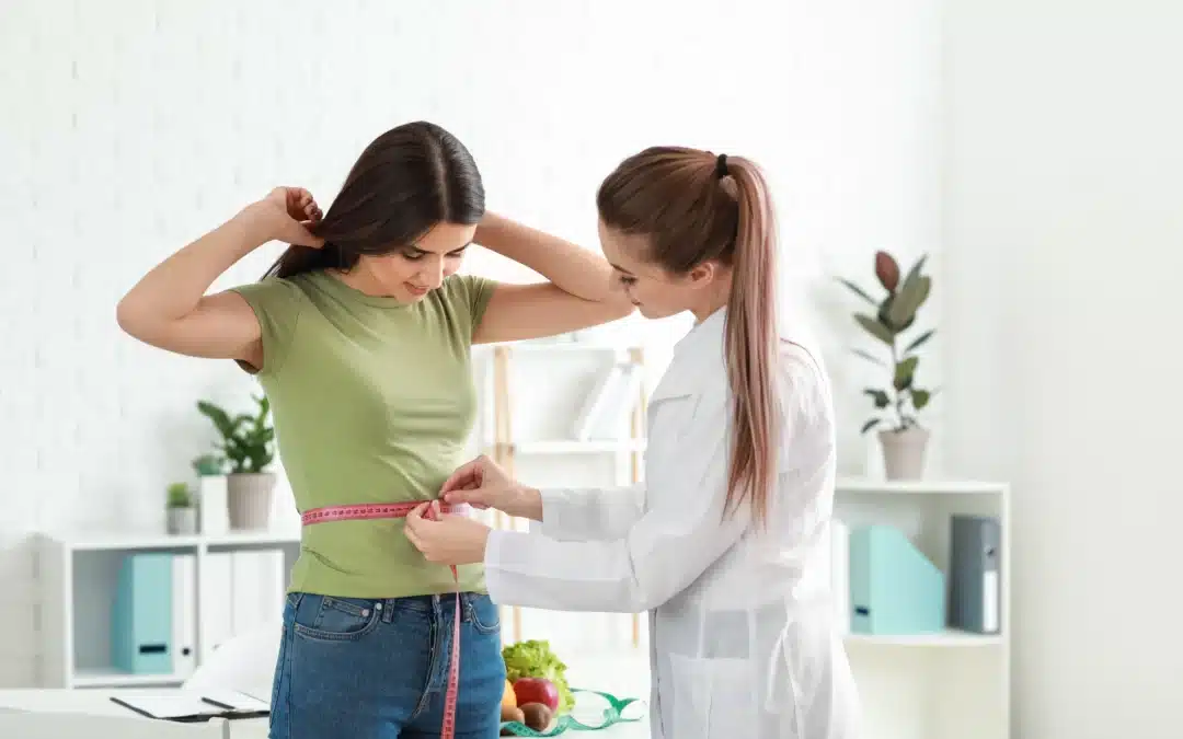 Dietitian using measuring tape to check woman’s waist for weight loss program results