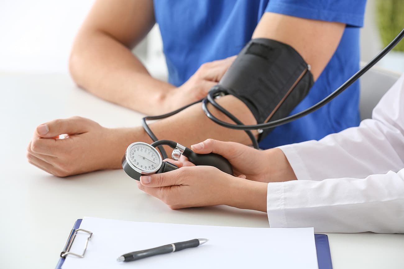 Doctor checking a patient's blood pressure with a manual cuff and gauge.